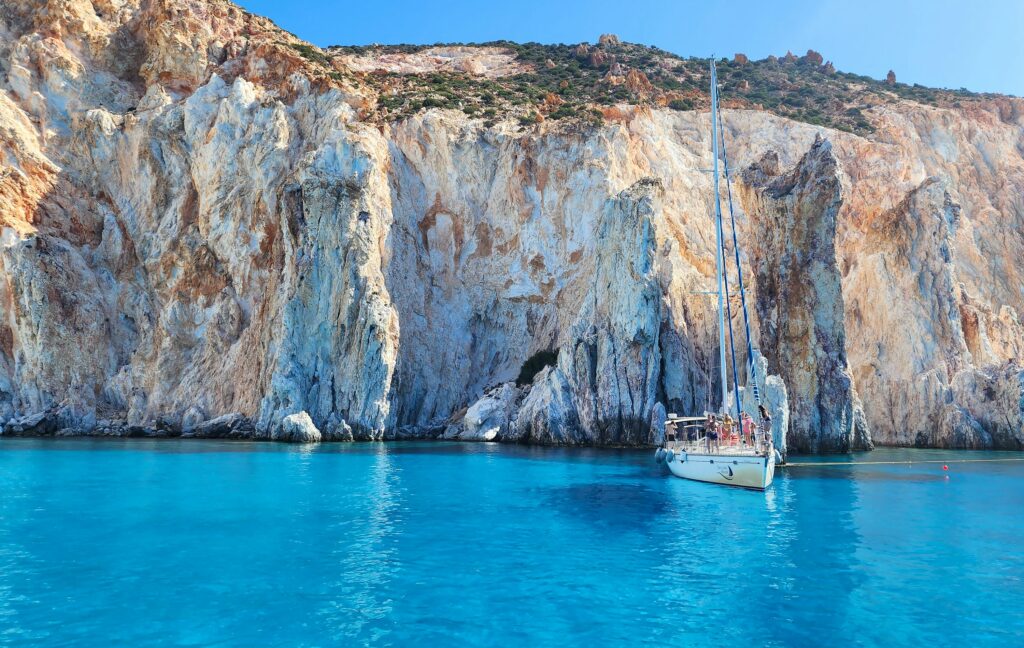 A boat floating in a body of water next to a mountain