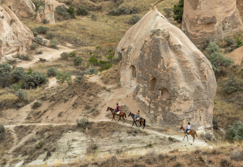 a group of people riding horses down a dirt road