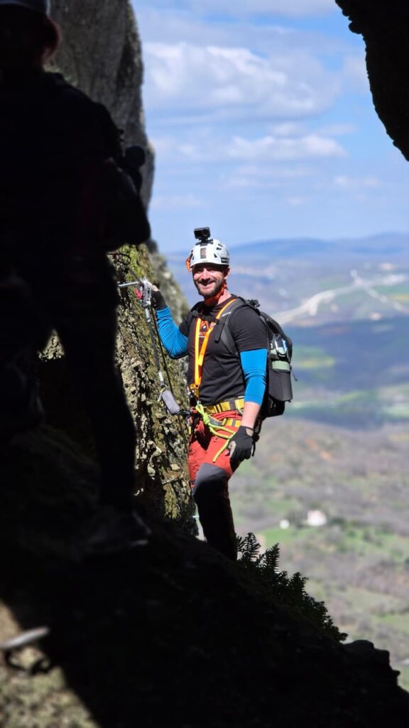 Συμμετέχων σε οργανωμένη Via Ferrata στα Μετέωρα με κράνος, εξοπλισμό ασφαλείας και εντυπωσιακό βραχώδες τοπίο.